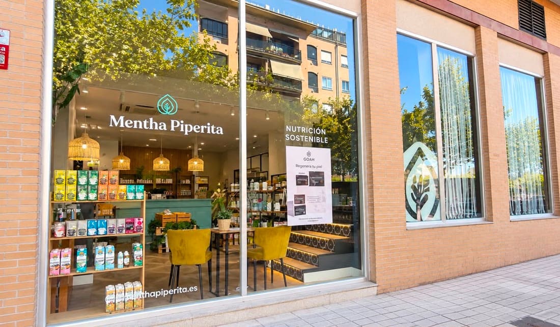 Escaparate de Mentha Piperita con el logotipo en el cristal y las estanterías de productos al fondo