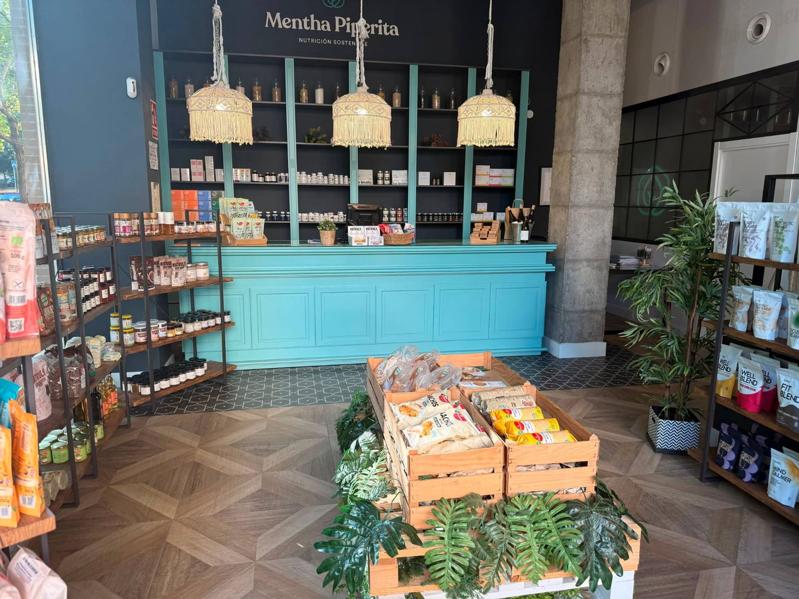 Interior de la tienda de Mentha Piperita en Badajoz: mostrador turquesa, lámparas de macramé y estanterías de productos